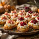 Whipped ricotta crostini topped with prosciutto and cranberry sauce on a rustic serving platter